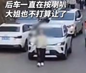 女子占道行走被鸣笛直接蹲车头挡路 后车无奈倒车绕行驶离