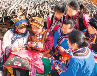 杨华珍（左二）在汶川县羌锋村与学徒们讨论羌绣技法。　　本文图片均由受访者提供
