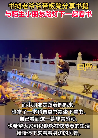 小朋友与书摊爷爷路灯下默契看书 一个探索未来一个品味过去