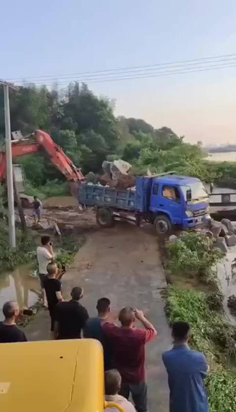 岳阳两辆满载卡车被推入河堵截洪水