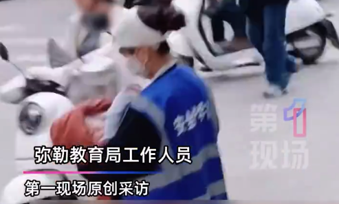 “家长都很积极，她说她可以” 家长抱婴儿在学校路边值护学岗