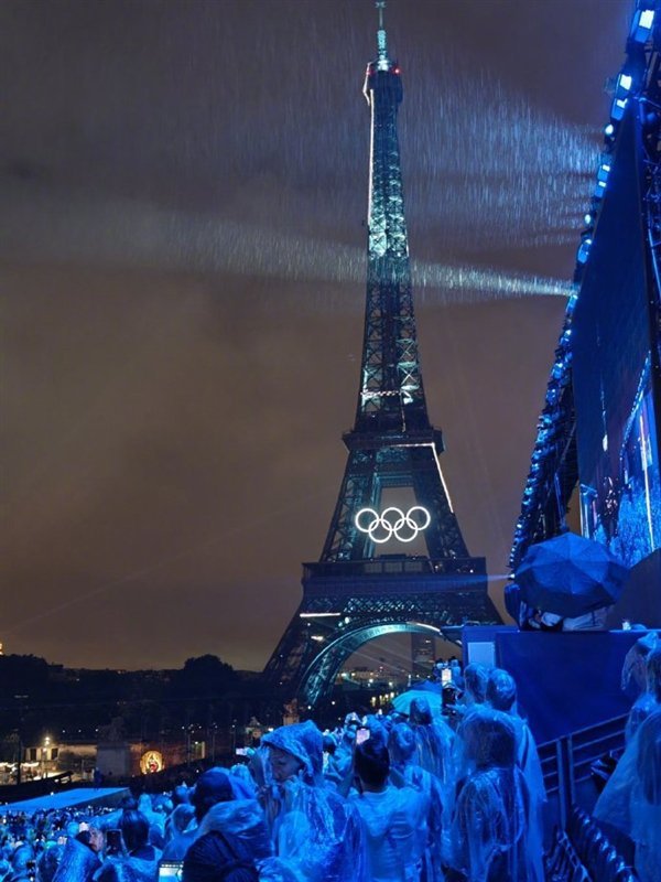 雷军身披雨衣现身巴黎奥运会开幕式 雨中见证历史时刻