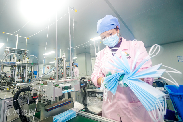1月26日，浙江省一家口罩生产车间内全自动口罩生产机不停运转，工人们正在加紧国内外订单。（图源：澎湃影像）