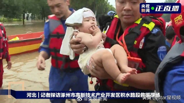 婴儿在救援者怀中吃手手 救援人员小心翼翼地抱着受困婴儿蹚过齐膝积水