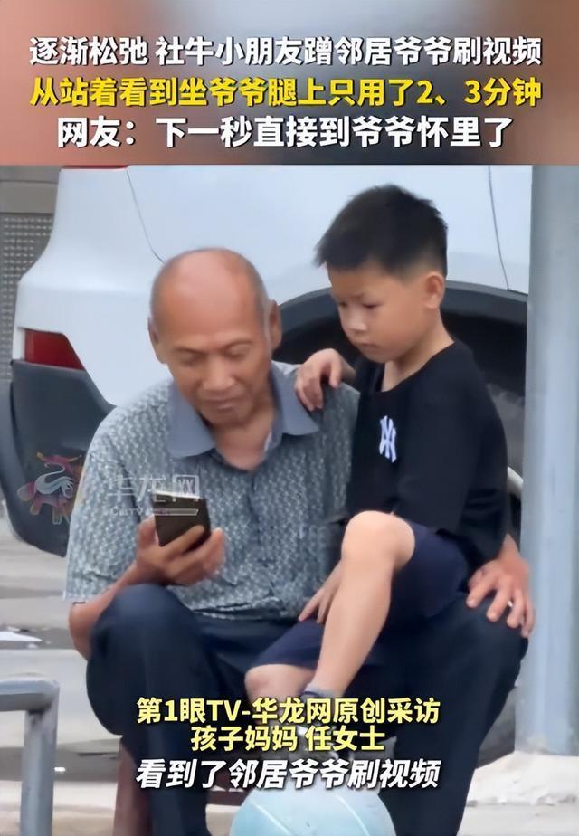 小朋友蹭邻居爷爷手机看视频 邻里和睦的温馨瞬间