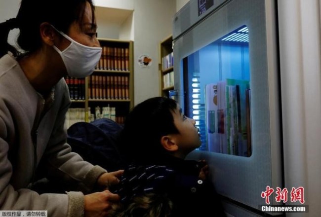 资料图：疫情期间，日本一所图书馆用紫外线给图书做消毒处理。
