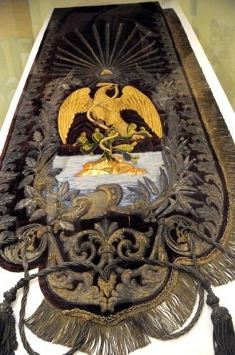 总统椅背后悬挂的旗帜，上有“神鹰衔蛇”图案（金丝线绣、金丝绒）