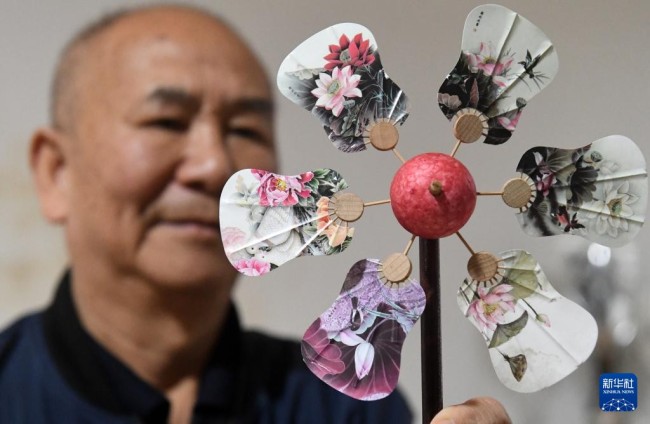 在广西桂林市灵川县定江镇，圆竹剖丝团扇制作技艺传承人黄硕夫在展示一款团扇文化创意产品（10月29日摄）。