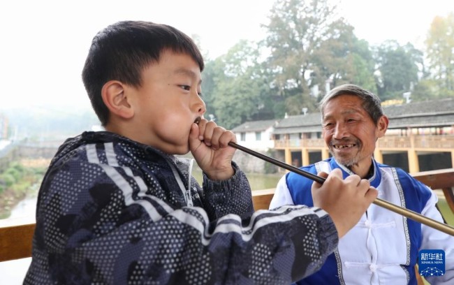 11月20日，在玉屏侗族自治县皂角坪街道枹木垅村，志愿者在指导一名学生学习长号唢呐吹奏技术。