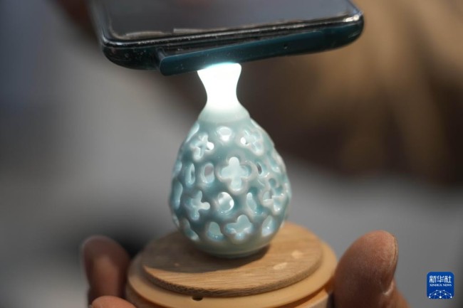 12月14日，王文化借助灯光展示一个微型陶瓷镂空花瓶。