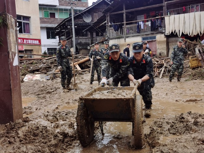 6月20日，武警官兵在受灾群众家中清理淤泥。  侯鲁晋 摄