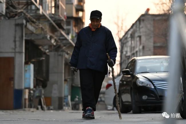  71岁的刘宝利拄着拐杖走向健身房。他在七八年间经历了两次脑梗，也没有放弃锻炼。
