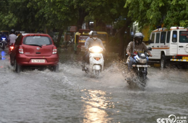 央视网消息：当地时间2021年6月4日，印度诺伊达，市民在雨中出行。当日，印度多个地区遭遇暴雨天气。视觉中国