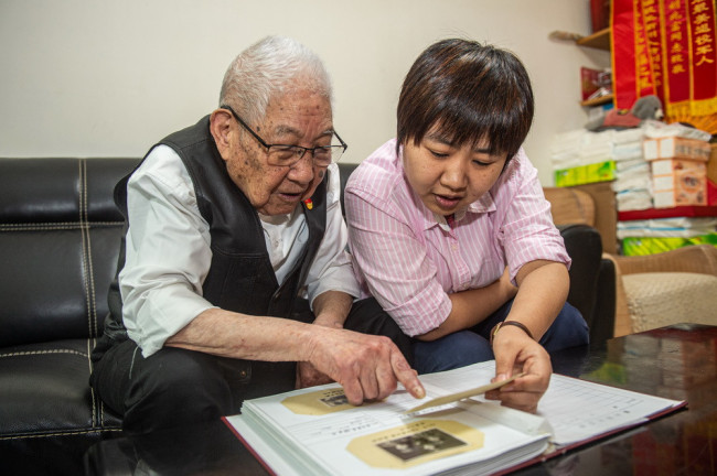 5月18日，胡兆富与孙女胡煜琦（右）翻看老照片，讲述过去的故事。