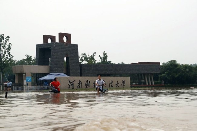 7月21日，河南财经政法大学前，市民准备骑车通过积水路面。