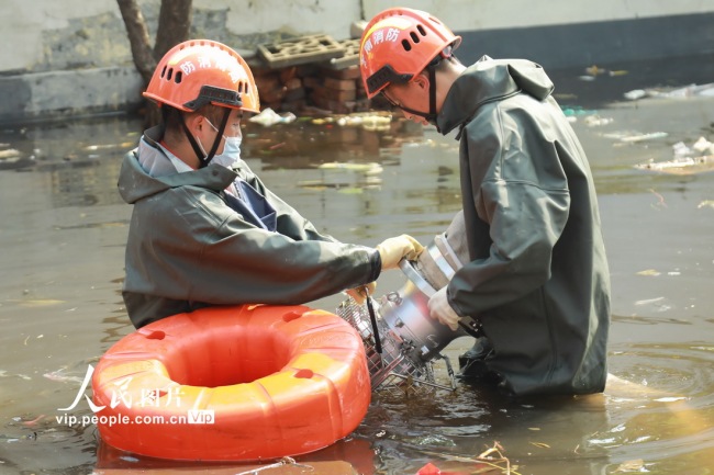 7月30日，河南省卫辉市健康路卫河河畔，消防员正在清理排涝泵。