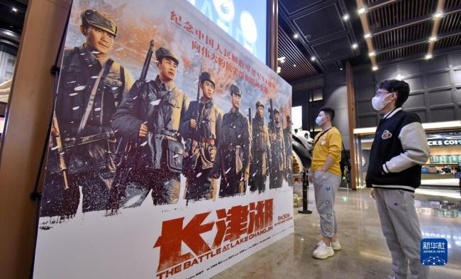 10月7日，两名年轻人在北京一家影院观看电影《长津湖》的海报。新华社记者 李欣 摄