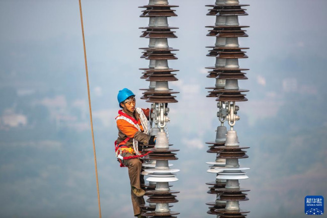 12月5日，在白鹤滩—江苏±800千伏特高压直流输电线路工程（重庆段）江津长江大跨越施工现场，工人在长江上空作业。
