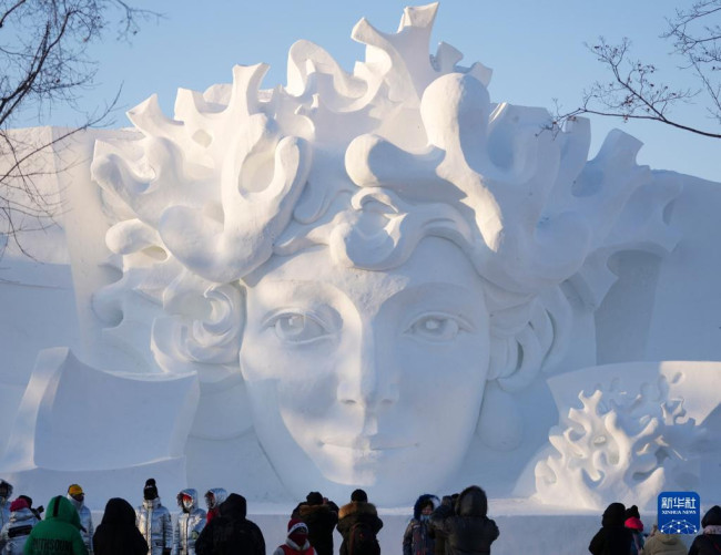 12月24日，在太阳岛雪博会园区，游客在雪雕前游览。