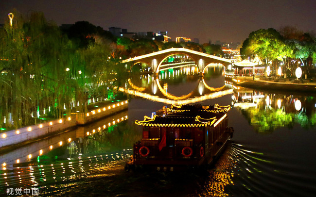 2021年12月31日晚，一艘载着游客的仿古游船在灯光璀璨的江苏苏州护城河上行驶。