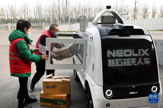 1月9日，在西咸新区沣西新城一物流中心，工作人员给无人配送车装货。