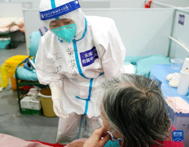 4月25日，在上海临港方舱医院，一名老年患者与医护人员交流自己过往用药史。