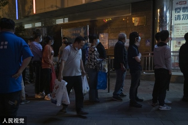 2022年4月24日晚，北京市朝阳区左家庄新源街京客隆店前，市民排队等待购物。