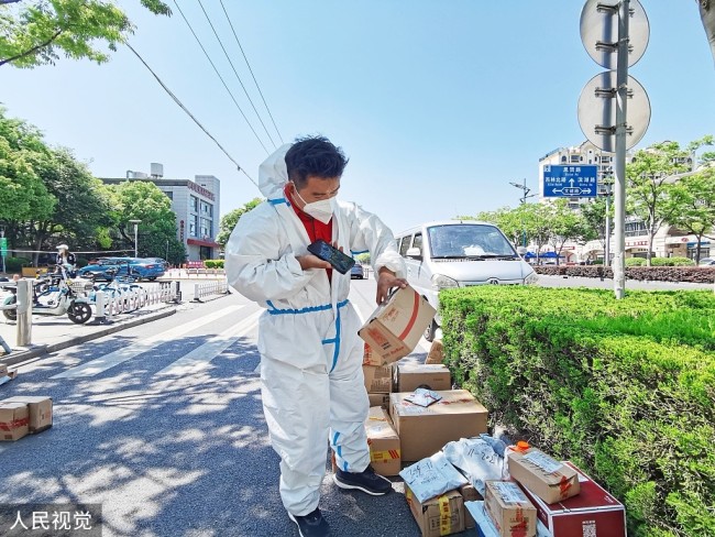 2022年5月6日,上海,松江區江學路邊的社區門口,一名京東快遞員正在