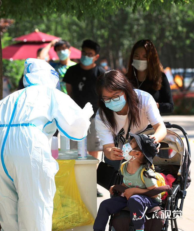 2022年5月15日，一名兒童在北京市朝陽區的一處核酸檢測采樣工作站進行咽拭子采樣。