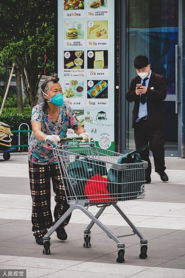 2022年5月20日，上海逐步恢复复工复产，徐汇区华泾镇无疫社区的居民走出小区，前往镇指定的永辉超市购物。