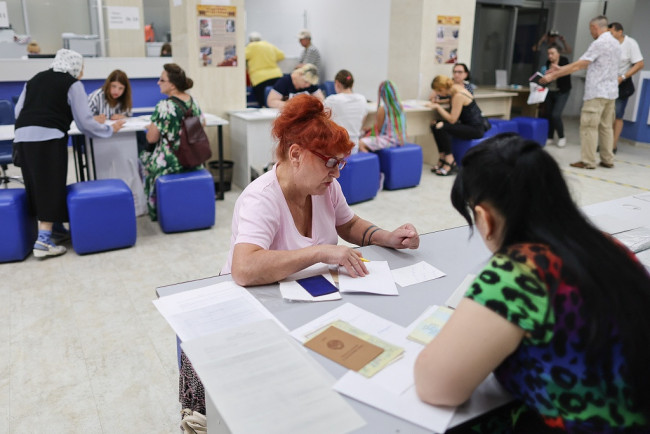 当地时间2022年7月13日，乌克兰赫尔松州，一名女性坐在申请俄罗斯公民身份的中心里。