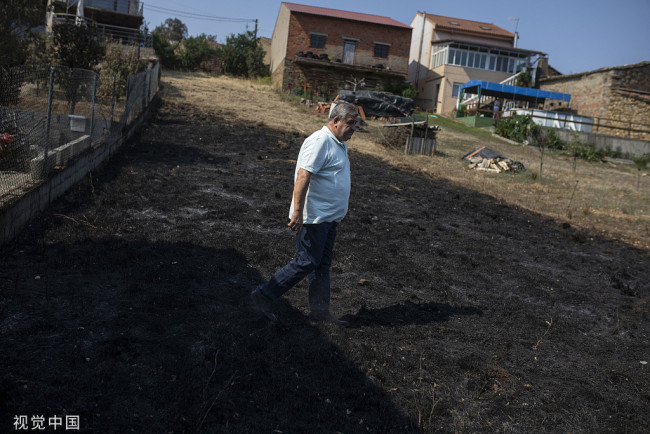 当地时间2022年7月19日，西班牙卡斯蒂利亚-拉曼恰，一名男子走过大火的受灾地区。