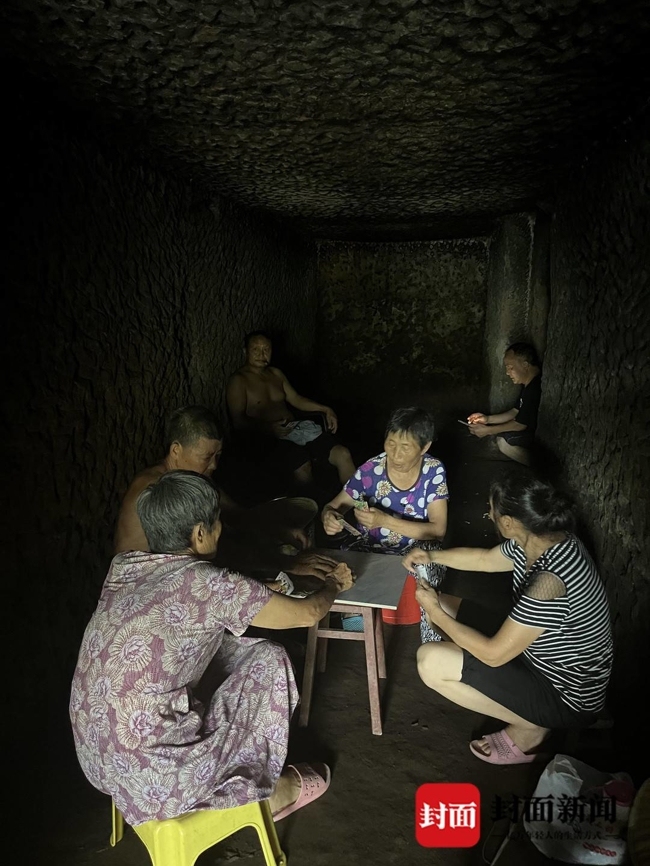 村民在墓穴躺坐一排乘凉:人多不怕，比空调好用