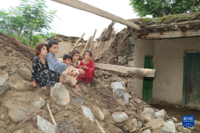 8月18日，孩子們坐在阿富汗努裏斯坦省被洪水損毀的房屋廢墟上。