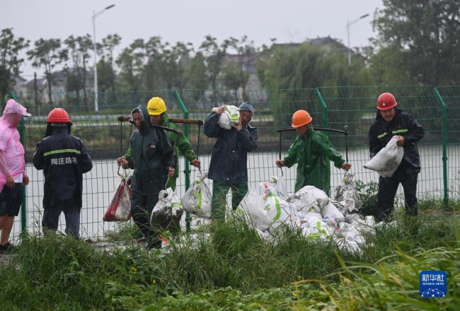 9月14日，在浙江嘉兴市嘉善县陶庄镇湖滨村，防汛人员在搬运沙袋加固河堤，防止台风引起的河水倒灌。新华社记者 徐昱 摄