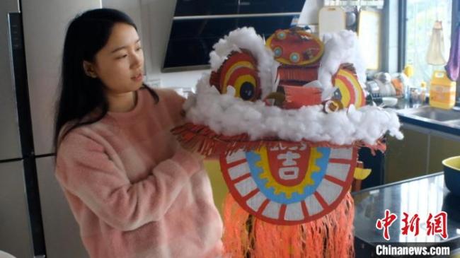 图为田媚媚正在展示自己用旧纸壳制作的“狮头”。　刘俊聪 摄