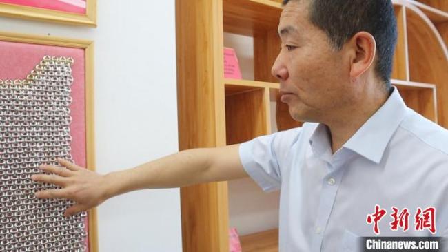 图为高伟展示用易拉罐拉环制作的“锁子甲”。　李文华 摄