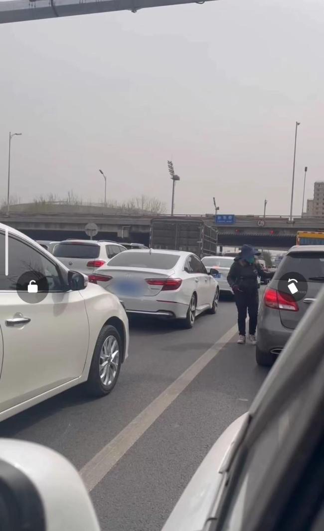 街头这样发小广告太危险 路上等红灯时钻到机动车道上往车窗插