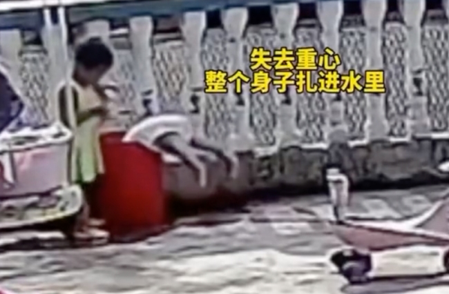 小孩玩水不慎栽进水桶