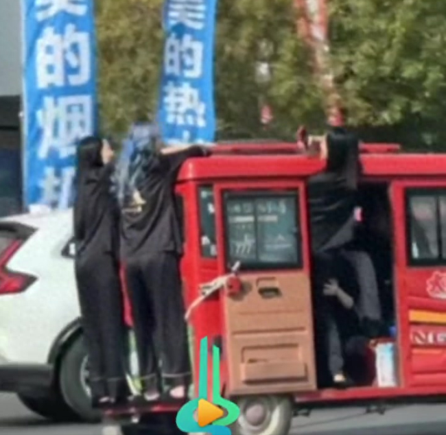 两名女生外挂在行驶的三轮车上