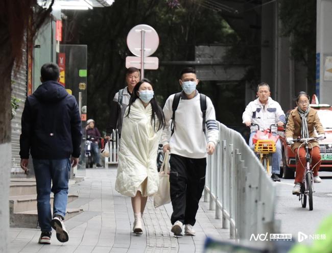 寒潮袭来气温骤降 广州街头小姐姐冻得裹被子