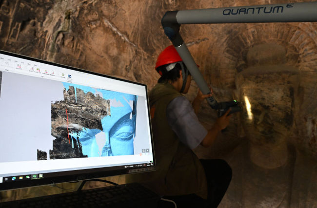 2025年4月9日，武漢大學(xué)文化遺產(chǎn)智能計算實驗室團(tuán)隊成員在魏字洞使用關(guān)節(jié)臂掃描儀對佛像進(jìn)行數(shù)字化掃描。圖片來源新華社