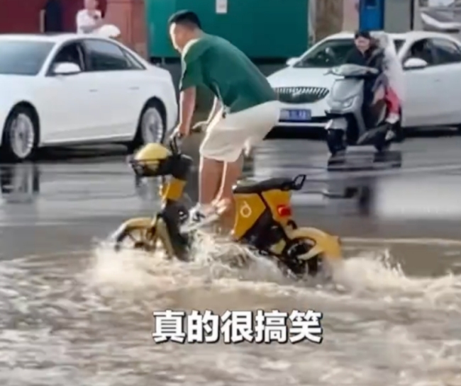 男子为不弄湿脚站在电动车上骑车