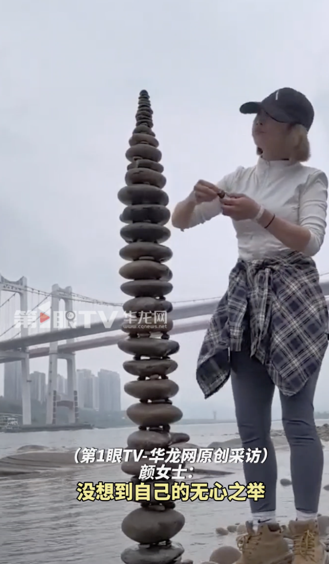 女生在江边搭石头塔垒到三十三层