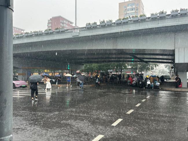 北京五棵松桥突降大雨 市民避雨外卖员坚守