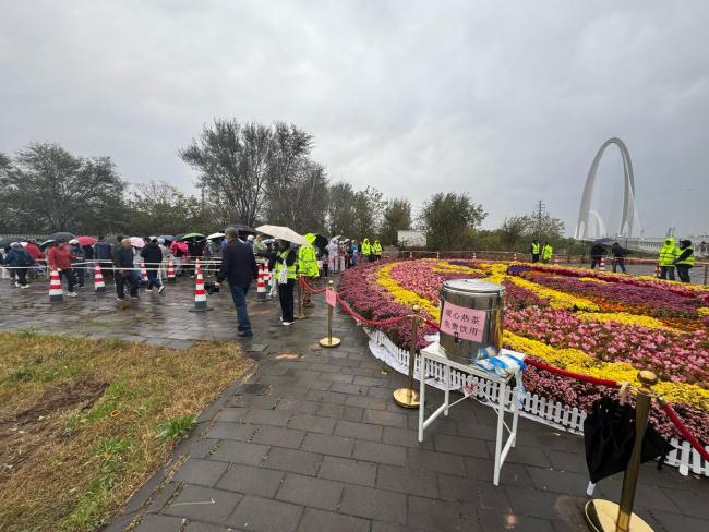 北京上百位市民雨中排队 接国庆鲜 花香传递节日温情