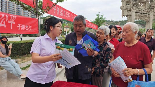 中国农业银行子洲县分行工作人员宣传反诈知识并发放小礼品吸引众多群众参与